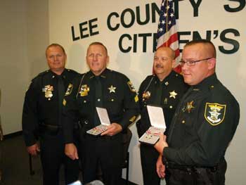 A group of people standing together in a row at the Badge of Bravery awards ceremony and holding their awards
