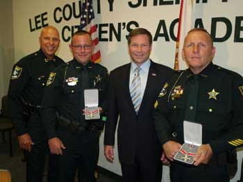 A group of people standing together in a row at the Badge of Bravery awards ceremony and displaying their awards