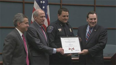 A group of people standing together and holding a Badge of Bravery award between them