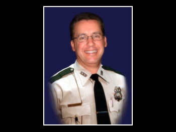 a head and shoulders portrait of a man in an officer's uniform smiling at the camera