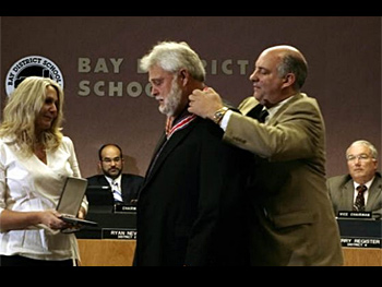 A man being presented with a Badge of Bravery award