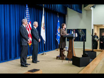 A woman standing at a podium on a stage and giving a speech.