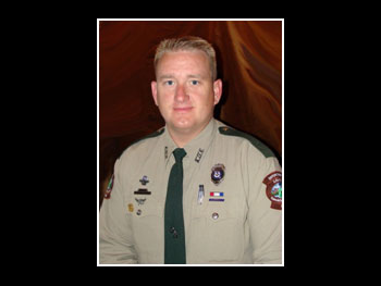 a head and shoulders view of a man in an officer's uniform, facing the camera and smiling slightly