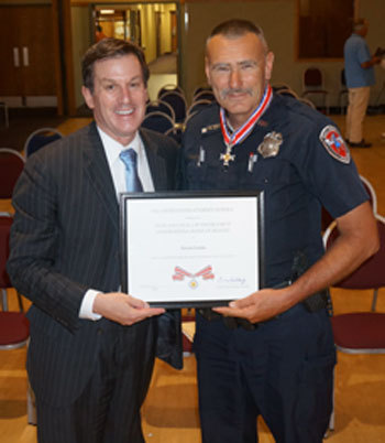 Two people standing together at the Badge of Bravery awards ceremony and smiling at the camera