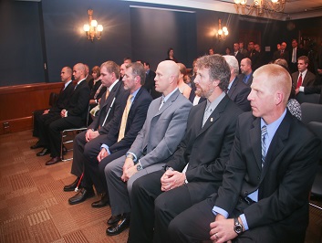 A group of people sitting in a row in the crowd at the Badge of Bravery awards ceremony
