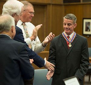 People applauding as a man receives a Badge of Bravery award