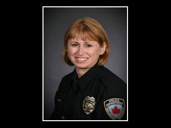 a head and shoulders photo of a female police officer in uniform smiling at the camera