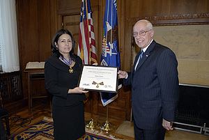 a man and woman standing in a room and holding a Medal of Valor award plaque between them