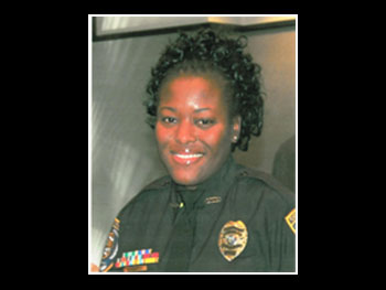 a head and shoulders view of a female police officer in uniform smiling at the camera