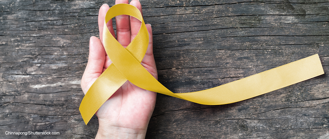 Hand holding yellow ribbon for suicide awareness and prevention