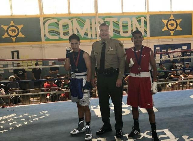 Capt. Michael Thatcher poses for a photo with two boxers competing in a match with the Compton Sheriff Youth Activities League.