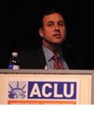 Man standing at a podium with an ACLU logo on it