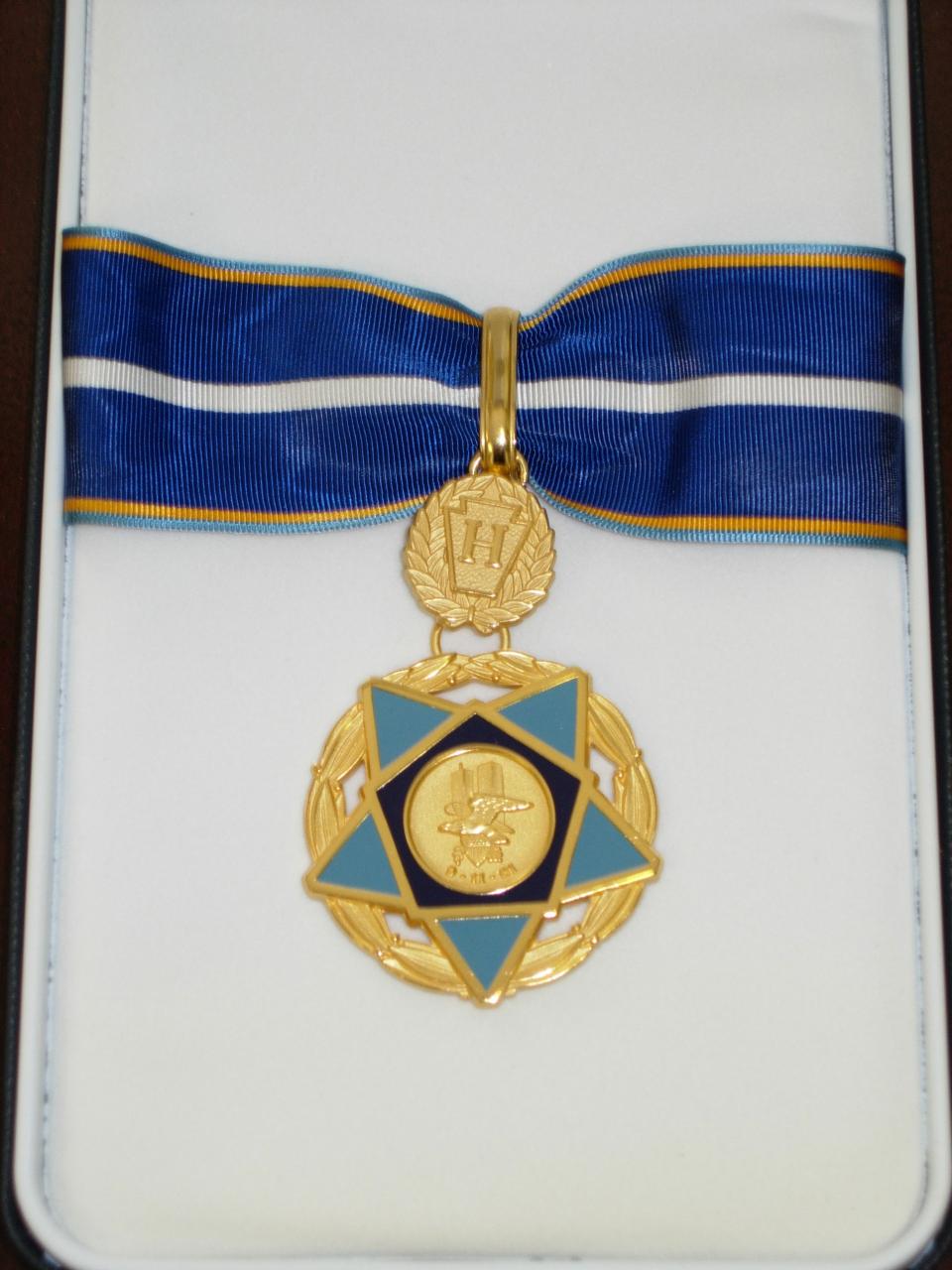 a blue and gold medal of valor on a blue ribbon with white and gold stripes